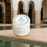 Amalia cream container on a stone ledge with a pool and arches in the background