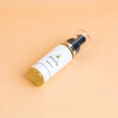 Bottle of Amala hair product on a peach background