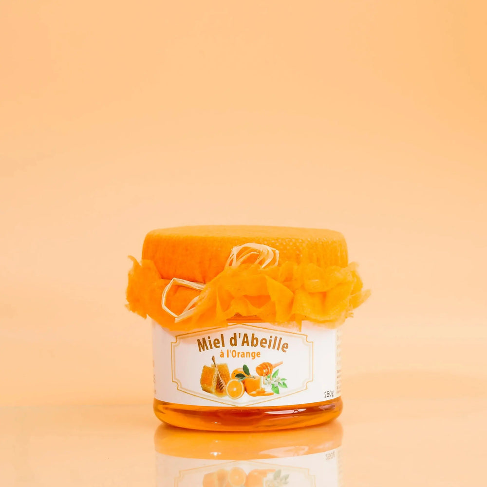 Jar of honey with a decorative bow on an orange background