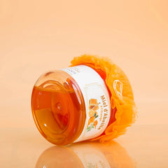 Jar of honey with a decorative orange cover on an orange background