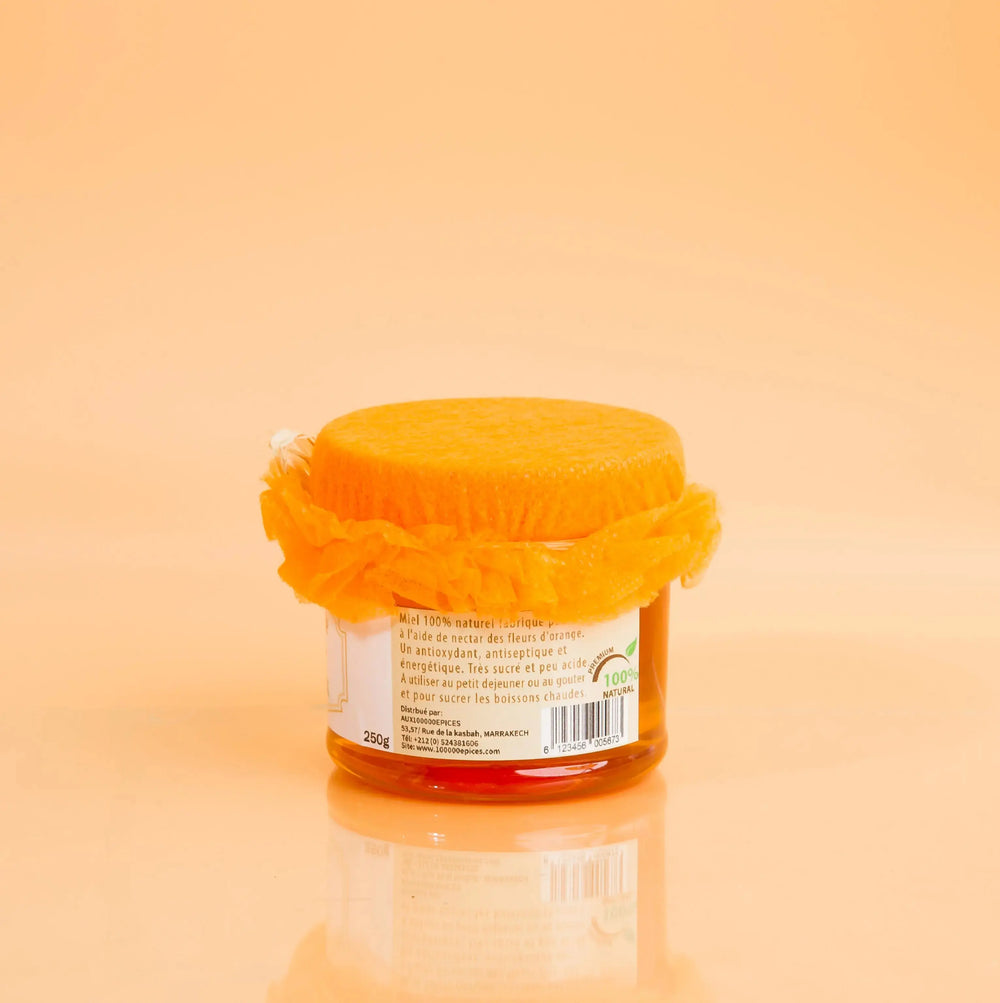 Jar of honey with a mesh cover on an orange background